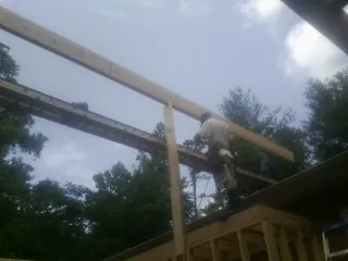 Carpenter setting a ridge beam over a new addition frame — Ice Dam Removal by Roofing Brothers in Mississippi State