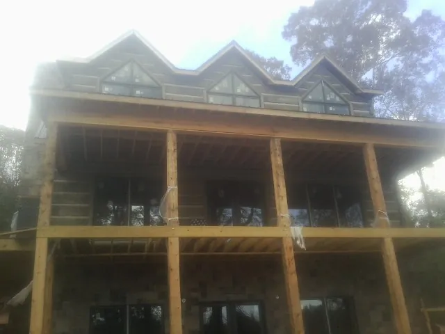 Dormers and porch framing on a large log home under construction — Roof Coating work by our crew in Mississippi State