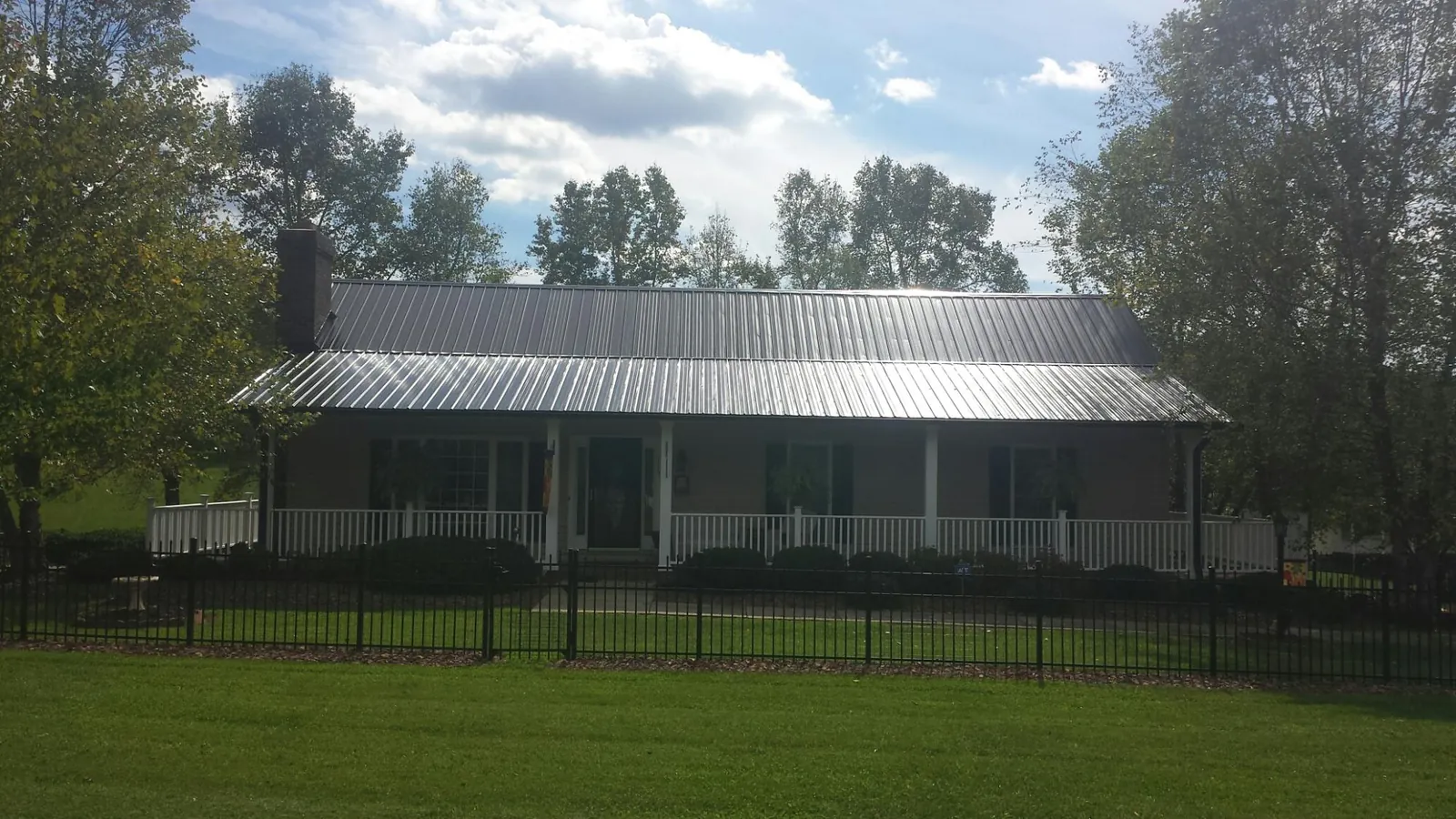 Gray metal roof on a brick ranch with a full width front porch — Gutter Guard Installation work by our crew in Mississippi State