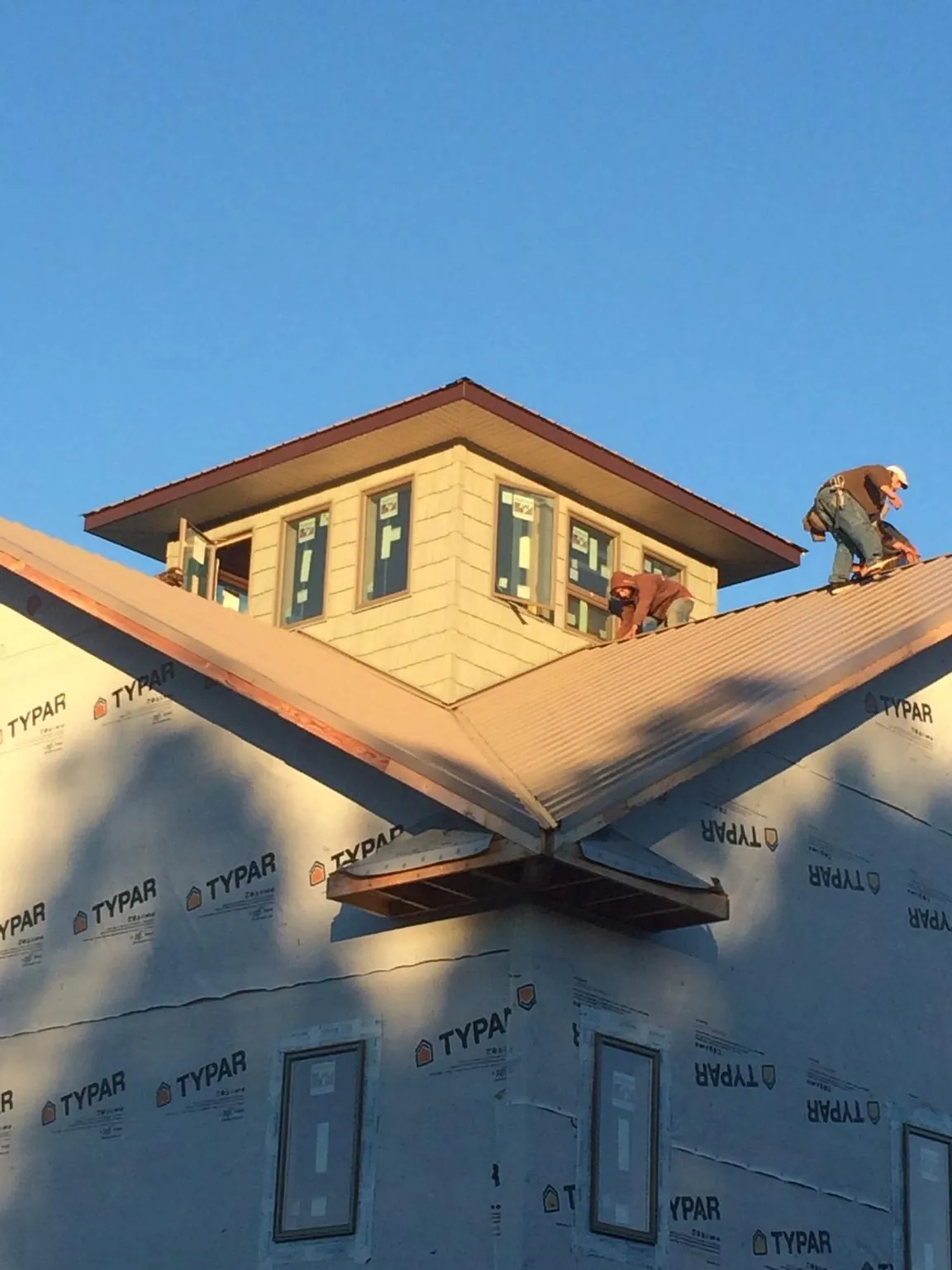 Roofers working around a rooftop cupola on a new metal roof at sunset — Roof Waterproofing in Mississippi State by Roofing Brothers